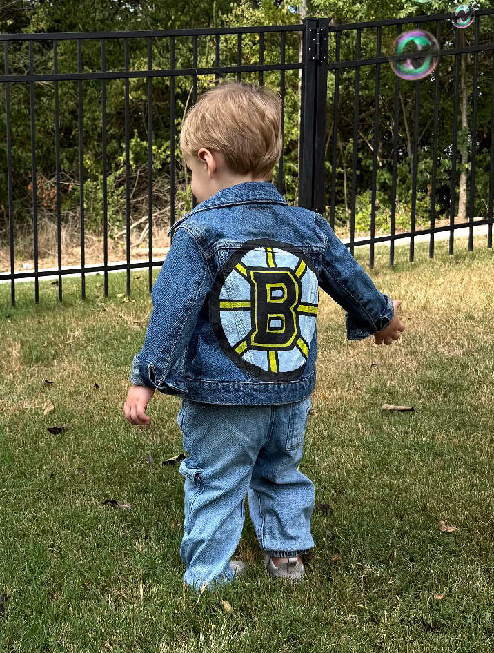 Child in a denim jacket with a logo walking outdoors with bubbles